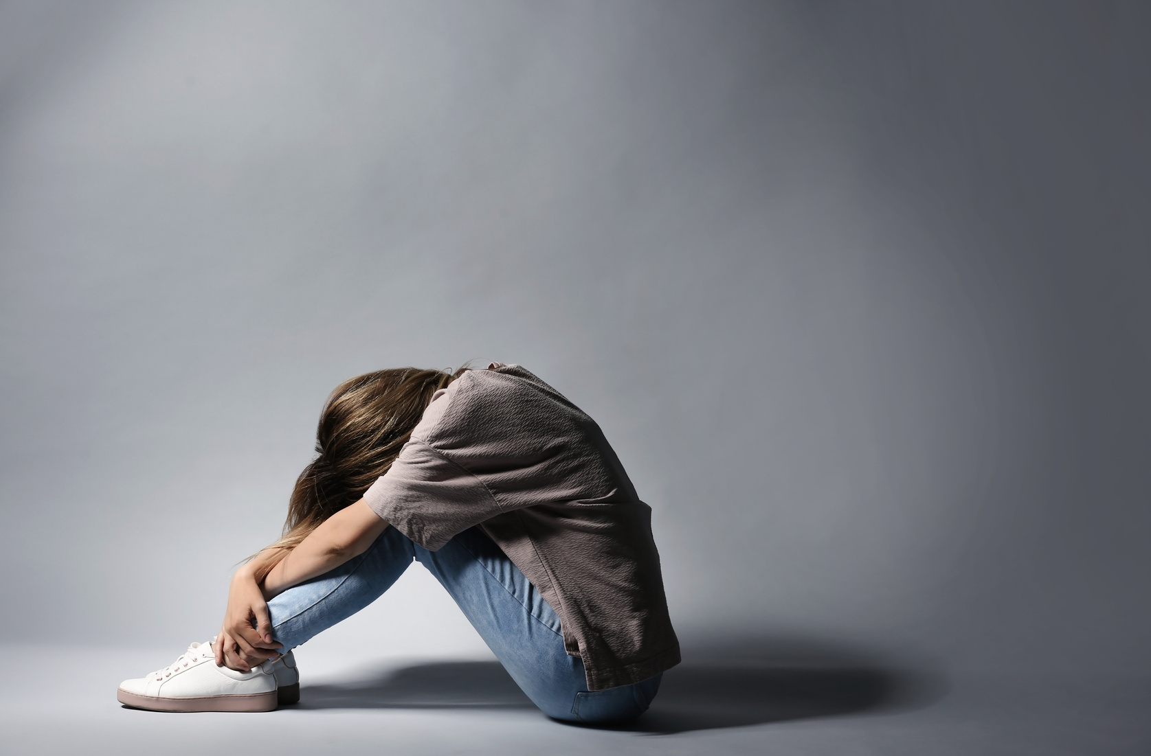 Lonely Depressed Woman Sitting on Grey Background